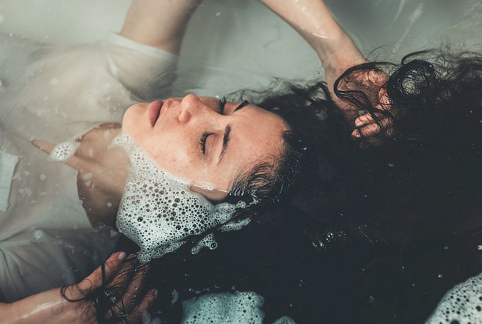 石鹸水で満たされたバスタブでくつろぐ女性の穏やかなクローズアップ
